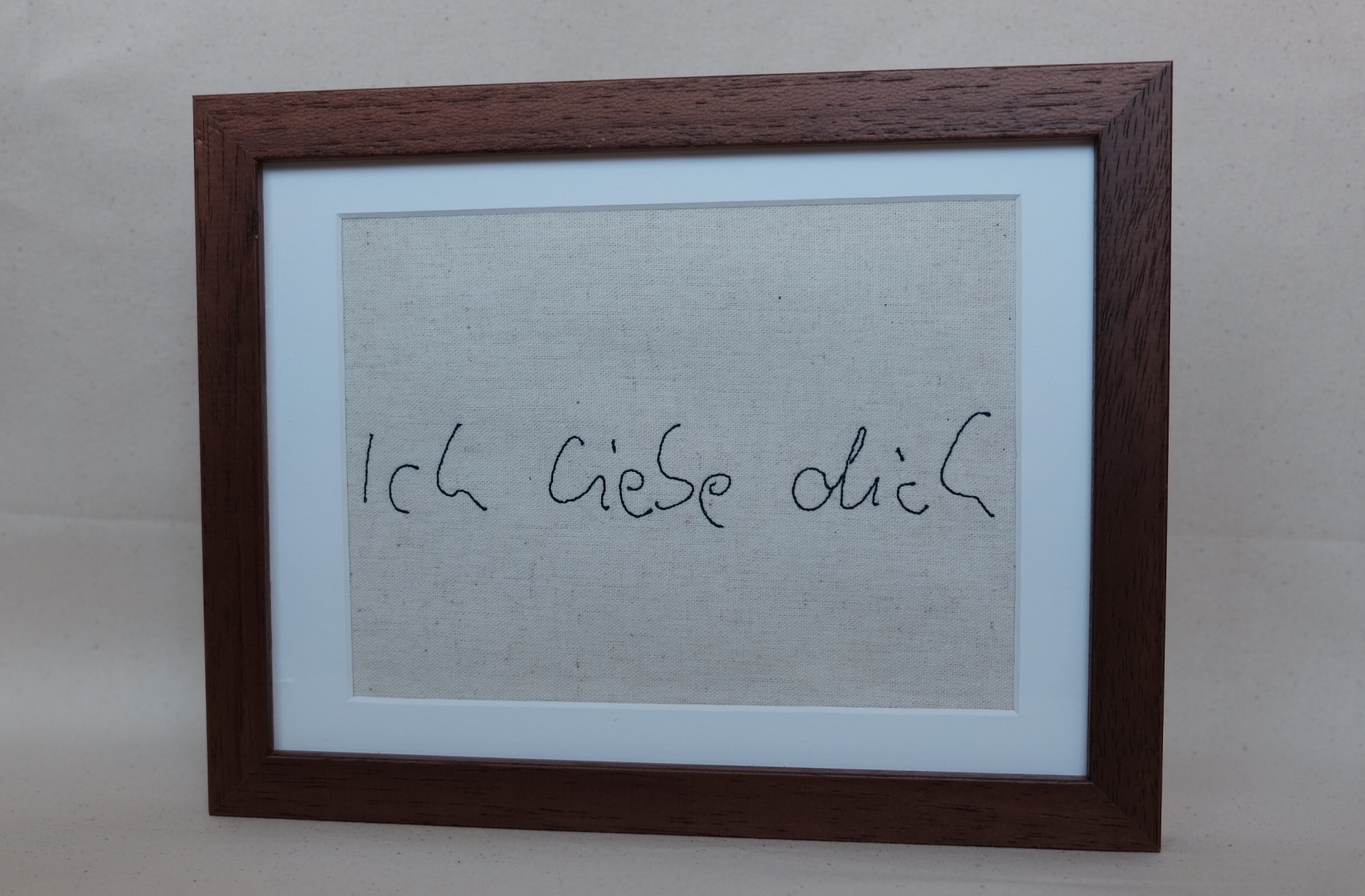 Gestickte handschriftliche Notiz „Ich liebe dich“ im dunklen Walnussrahmen